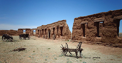 Adobe ruins and wooden wagon remains at Fort Union National Monument.